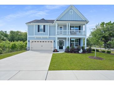 Charming two-story home featuring a light blue facade, inviting front porch, and well-manicured lawn at 1004 Saltwater Cir, Johns Island, SC 29455
