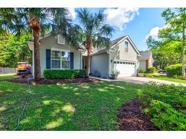 Charming single-story home with a well-manicured lawn, palm trees, and an attached two-car garage at 1231 Wild Olive Dr, Mount Pleasant, SC 29464