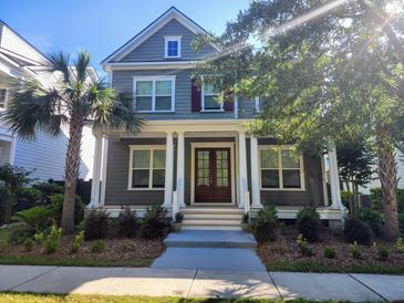Charming two-story home with gray siding, white columns, front porch, landscaped yard, and mature palm trees at 1363 Rivella Dr, Mount Pleasant, SC 29464