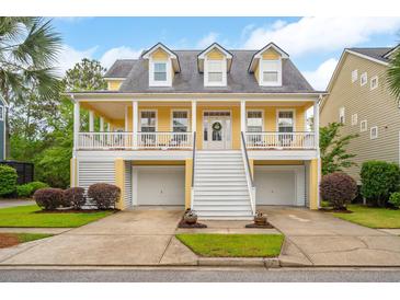 Charming yellow two-story home featuring a welcoming front porch and ground level two-car garage at 2267 N Marsh Dr, Mount Pleasant, SC 29466