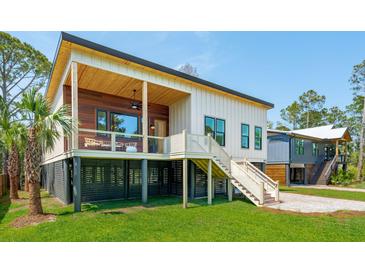 Modern home with unique architecture, featuring elevated design, wood accents, and a lush green lawn at 1012 E Erie Ave, Folly Beach, SC 29439