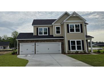 Beautiful two-story home with stone accents, a spacious three-car garage, and a well-manicured lawn at 114 Captains Creek Ln, Ridgeville, SC 29472