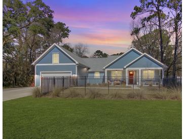 Charming blue home with a red door, black fence, and a well-manicured lawn under a lovely sunset at 1543 Scott Hill Rd, James Island, SC 29412