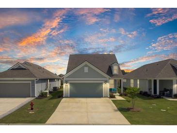 Charming single-Gathering home with a two-car garage and well-manicured lawn under a dramatic colorful dusk sky at 350 Dahlia Row Dr, Summerville, SC 29486
