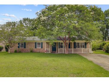 Charming brick home featuring a well-manicured lawn and beautiful, mature trees at 114 Stewart St, Goose Creek, SC 29445