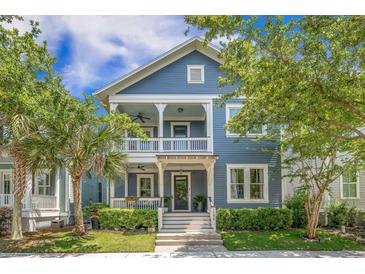Charming blue two-story home boasts a welcoming porch and beautifully landscaped front yard on a sunny day at 1588 Paradise Lake Dr, Mount Pleasant, SC 29464