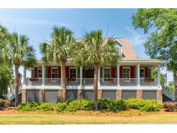 Charming home featuring a spacious front porch, brick foundation, and beautiful palm trees at 16 Fairway Village Ln, Isle of Palms, SC 29451