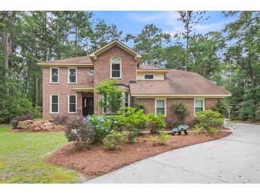 Charming brick two-story home featuring a well-manicured lawn and lush landscaping at 320 Compton Xing, Summerville, SC 29485