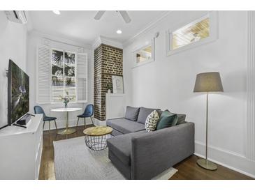 Cozy living room with a grey sectional sofa, exposed brick, and a window for natural light at 33 Pitt St # 3, Charleston, SC 29401