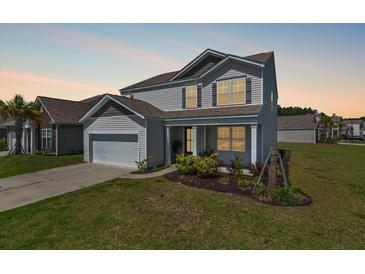 Charming two-story home featuring a manicured lawn and attached two-car garage at 411 Bering Ln, Summerville, SC 29486