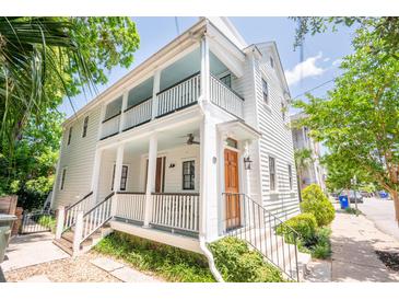 Inviting two-story home featuring a double porch, white siding, manicured landscaping, and natural light at 50 South St, Charleston, SC 29403