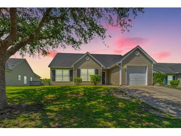 Charming single-story home featuring a well-manicured lawn and inviting curb appeal at sunset at 5042 Thornton Dr, Summerville, SC 29485