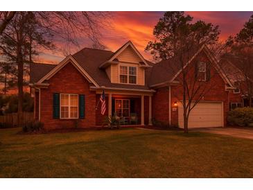 Charming two-story brick home with a well-manicured lawn and inviting front porch at dusk at 106 Sago Palm Ct, Summerville, SC 29483
