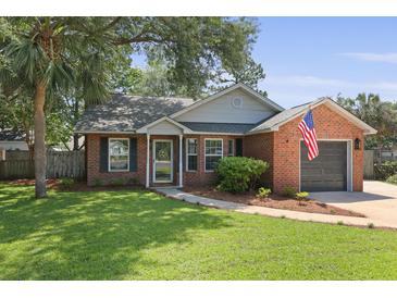 Charming brick home with manicured lawn, mature trees, and American flag at 1308 Cadet Ct, Mount Pleasant, SC 29466