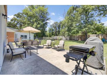 Inviting back patio with dining set, lounge chairs, grill, and spacious yard perfect for outdoor entertaining at 3428 Plaza Ln, North Charleston, SC 29420