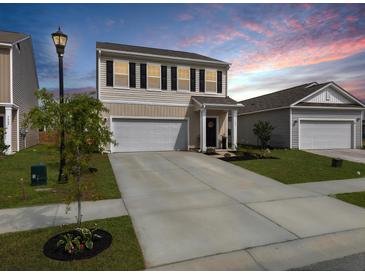 Charming two-story home with a well-manicured lawn and a two-car garage and inviting entrance at 5003 Ferry Field Dr, Summerville, SC 29485