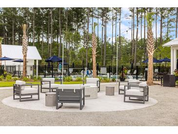 Outdoor lounge area features comfortable seating, modern fire pit, and a tranquil wooded backdrop at 708 Breakers Reef Ln, Huger, SC 29450