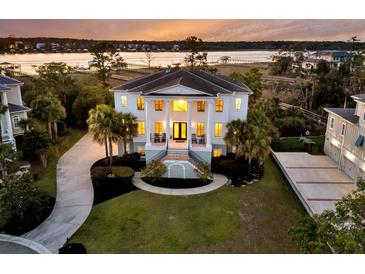Elegant two-story home boasts grand columns, a landscaped yard, and a serene waterfront view at sunset at 1720 Bowline Dr, Mount Pleasant, SC 29466