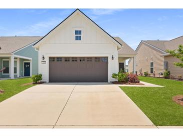 Charming home featuring a two-car garage, neutral siding, and meticulously manicured landscaping at 220 Garden Gate Way, Summerville, SC 29486