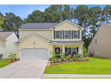 Charming two-story home with yellow siding, black shutters, well-manicured lawn and beautiful landscaping at 230 Sweet Alyssum Dr, Ladson, SC 29456