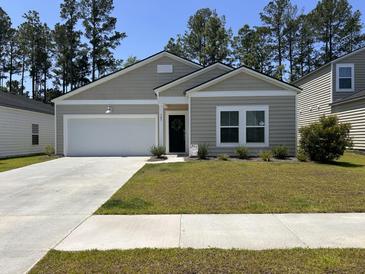 Charming single-story home with a well-manicured lawn and attached garage at 305 Camellia Bloom Dr, Moncks Corner, SC 29461