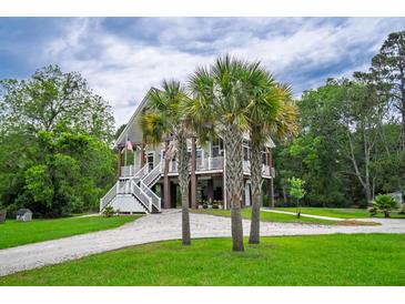 Charming raised beach house with white stairs and palm trees in the front yard at 1064 Blackbear Dr, Edisto Island, SC 29438