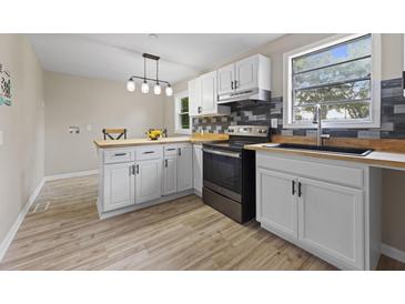 Bright kitchen features white cabinets, butcher block countertops, stainless steel appliances, and luxury vinyl flooring at 121 Harrison St, Varnville, SC 29944
