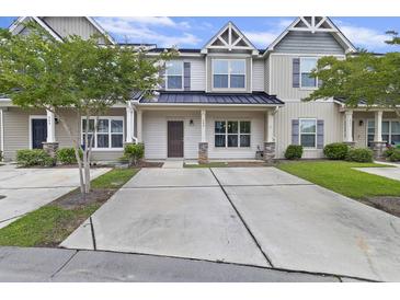 Charming townhome featuring a metal roof, well-maintained landscaping, and a spacious concrete driveway at 242 Swallowtail Ln, Goose Creek, SC 29445