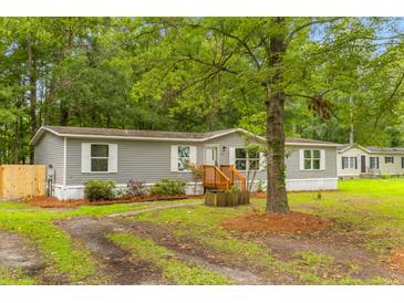 Charming single-story home featuring gray siding, white shutters, a wood porch and a lush green lawn at 201 Frank St, Summerville, SC 29483
