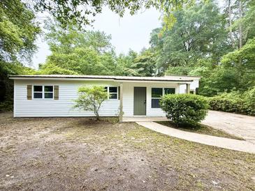 Charming single-story home with vinyl siding and a welcoming front entrance, nestled in a lush, wooded setting at 208 Orange St, Walterboro, SC 29488