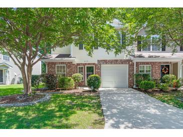 Charming two-story home featuring a single-car garage, brick accents, and a well-maintained front yard with lush trees at 215 Jackson St, Goose Creek, SC 29445
