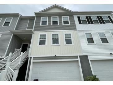 Townhome exterior with a white garage door, various toned sidings, and a staircase leading to the front door at 313 Lanyard St, Johns Island, SC 29455