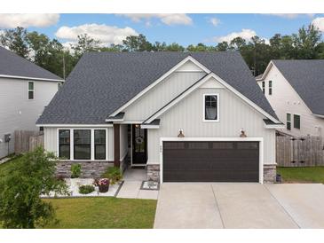 Charming single-Gathering home featuring stone accents, a dark two-car garage, and manicured landscaping at 404 Omaha Dr, Moncks Corner, SC 29461