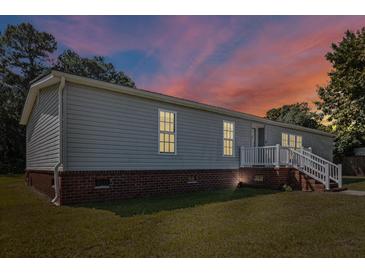 Charming single-Gathering home featuring vinyl siding, brick foundation and a cozy front porch with white railing at 513 Pauline Dr, Bonneau, SC 29431