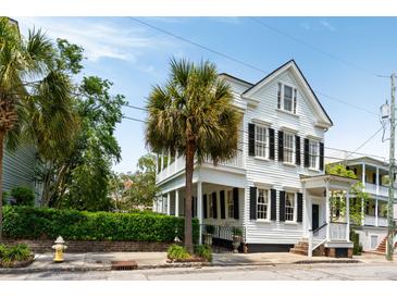 Charming two-story home with white siding, black shutters, and lush palm trees, showcasing classic elegance at 16 Trumbo St, Charleston, SC 29401