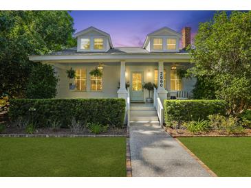 Charming two-story home featuring a well-manicured lawn and inviting front porch with elegant columns and dormer windows at 2060 Wappoo Hall Rd, Charleston, SC 29412