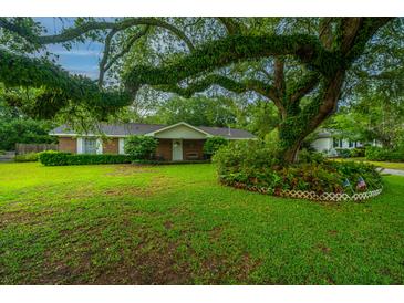 Charming brick home with a lush lawn and a large, mature tree providing shade at 930 Stiles Dr, Charleston, SC 29412