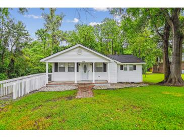 Charming single-story home boasts a well-manicured lawn, brick pathway, and a welcoming front porch at 106 N Pine St, Summerville, SC 29483