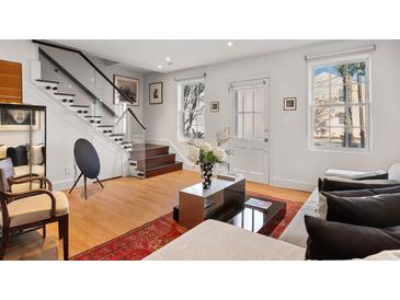 Bright living room featuring hardwood floors, modern stairs with glass railing, and contemporary decor at 301 Broad St # 1, Charleston, SC 29401