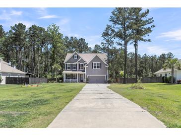 Charming two-story home with a well-manicured lawn and long driveway leading to the garage at 404 Bowstring Dr, Huger, SC 29450