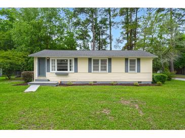 Charming single-story home with light yellow siding, gray shutters, and a well-maintained green lawn at 407 Raysor St, Saint George, SC 29477