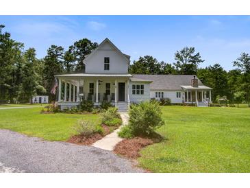 Stunning white farmhouse with a charming front porch and lush, well-maintained landscaping at 105 Bobcat Ln, Ravenel, SC 29470