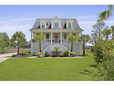 Charming two-story beach home with a lush green lawn, a picturesque porch, and beautiful palm trees at 1216 Rivers Reach Dr, Charleston, SC 29492
