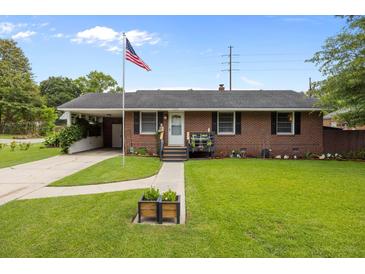 Charming brick home features a well-manicured lawn and inviting front porch with patriotic American flag at 2651 Martha Dr, North Charleston, SC 29405