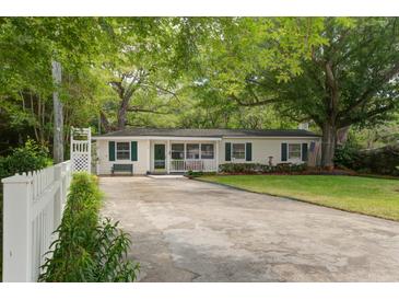 Charming single-story home featuring a well-manicured lawn, mature trees, and a cozy front porch at 344 Lantana Dr, Charleston, SC 29407