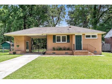 Charming brick home featuring a well-manicured lawn, green door, and a convenient covered parking area at 5172 Sterrett St, North Charleston, SC 29405