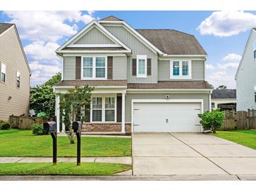 Two-story home showcasing a well-manicured lawn, gray siding, and a two-car garage under a partly cloudy sky at 535 Crossland Dr, Moncks Corner, SC 29461