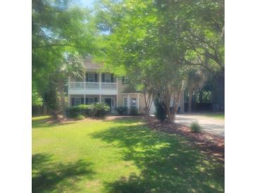Charming two-story home with a manicured lawn, mature trees, and a welcoming front porch at 5440 Rock Creek Ct, North Charleston, SC 29420