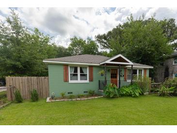 Charming home with a green exterior, a cozy front porch, and a well-maintained lawn at 716 White Oak Dr, Charleston, SC 29407
