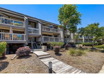 Inviting condo exterior featuring boardwalk, multiple decks, and lush landscaping at 1605 Live Oak Park, Seabrook Island, SC 29455